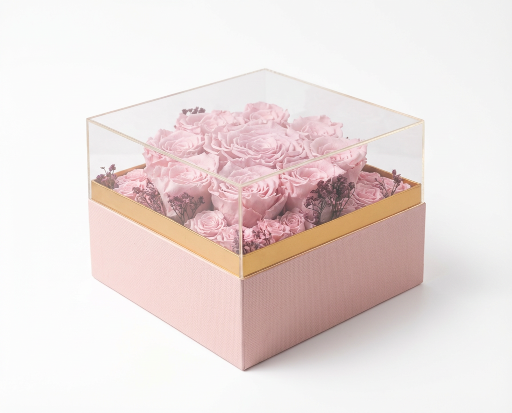 Pink flowers in a transparent box with a gold rim on a white background