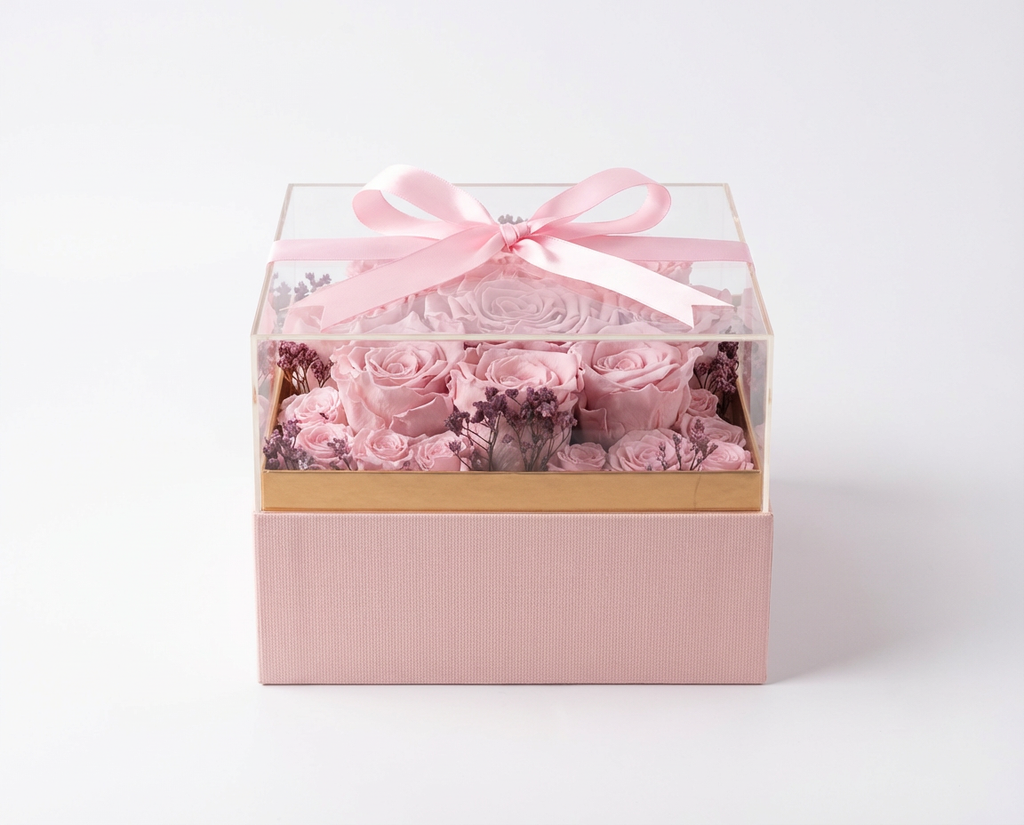 Pink roses in a transparent box with a pink ribbon on a white background